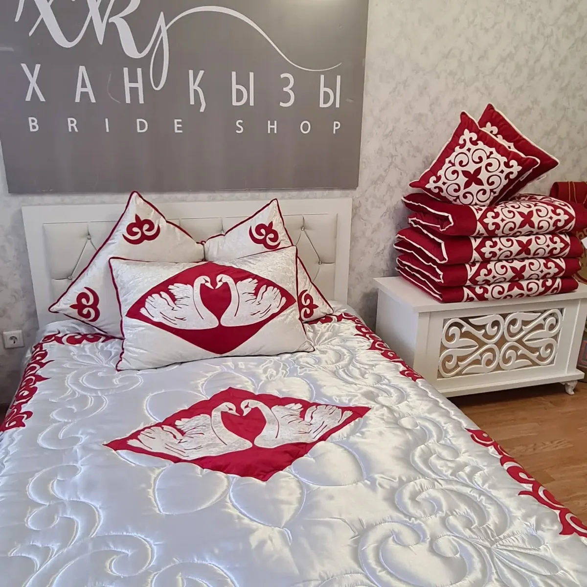 Red and white ornamental bedding set styled against the Xan Kyzy logo wall