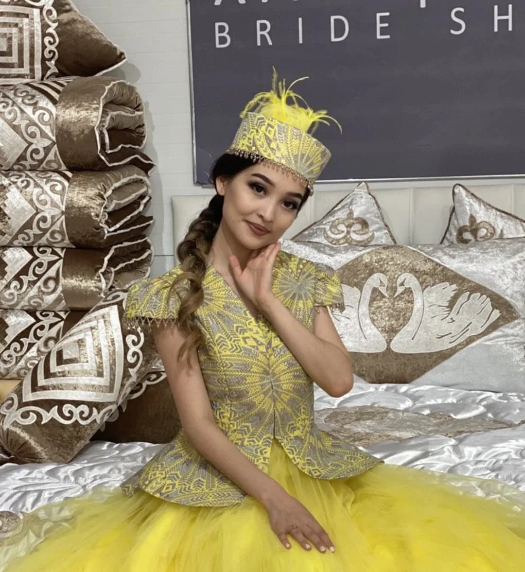 Model in traditional dress inside the Xan Kyzy boutique next to embroidered swan textiles